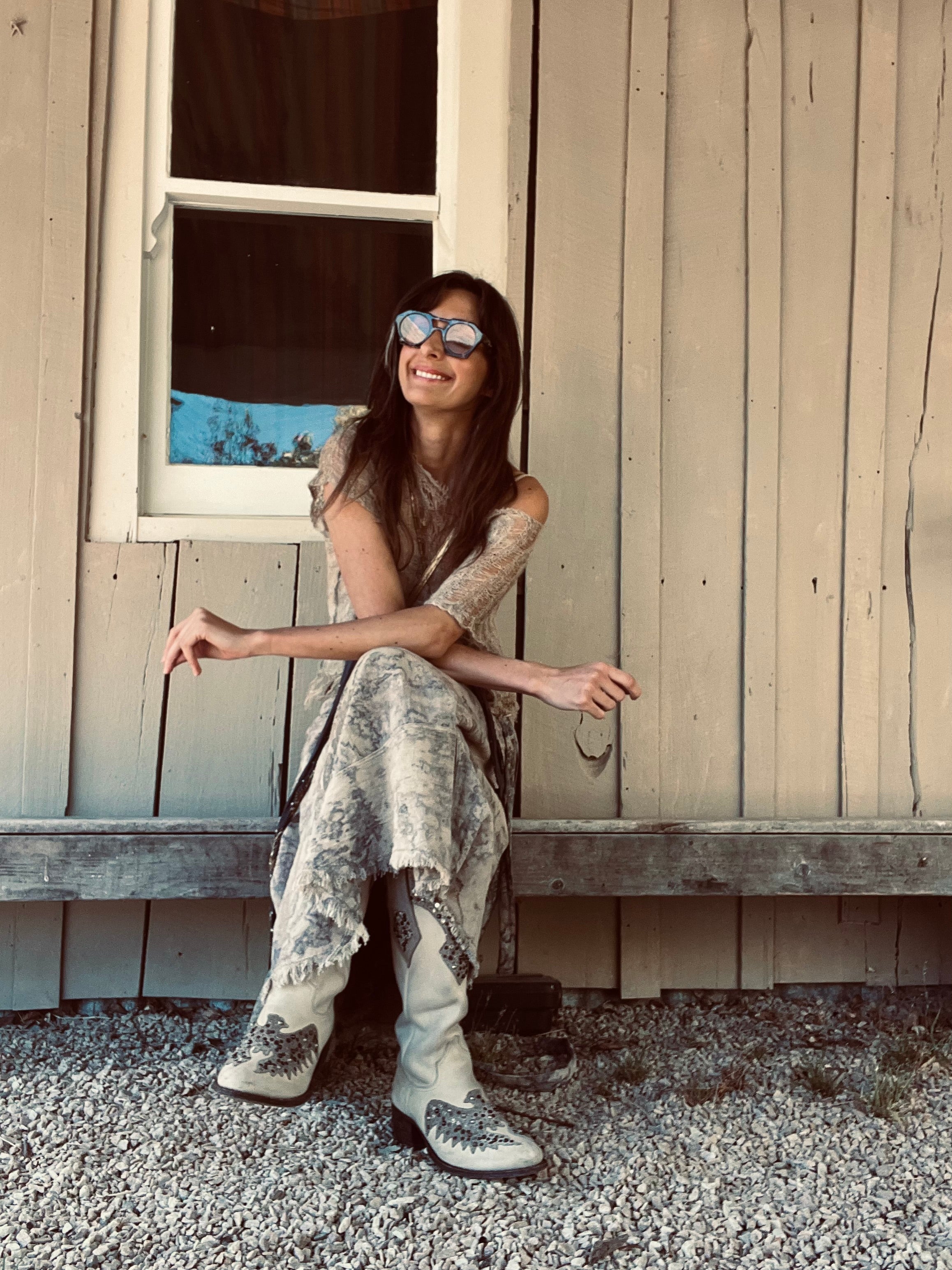 ARTNA founder Tamara wearing artisan hand-dyed clothing beside a rustic wooden wall, reflecting handmade craftsmanship and slow living