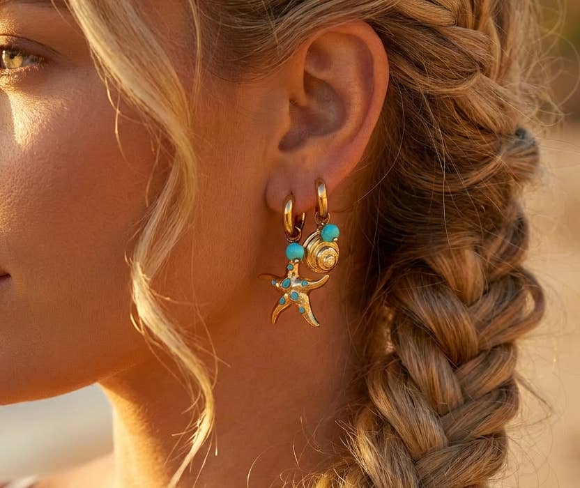 Gold dangle earrings — one starfish with a blue bead, one nautilus shell.