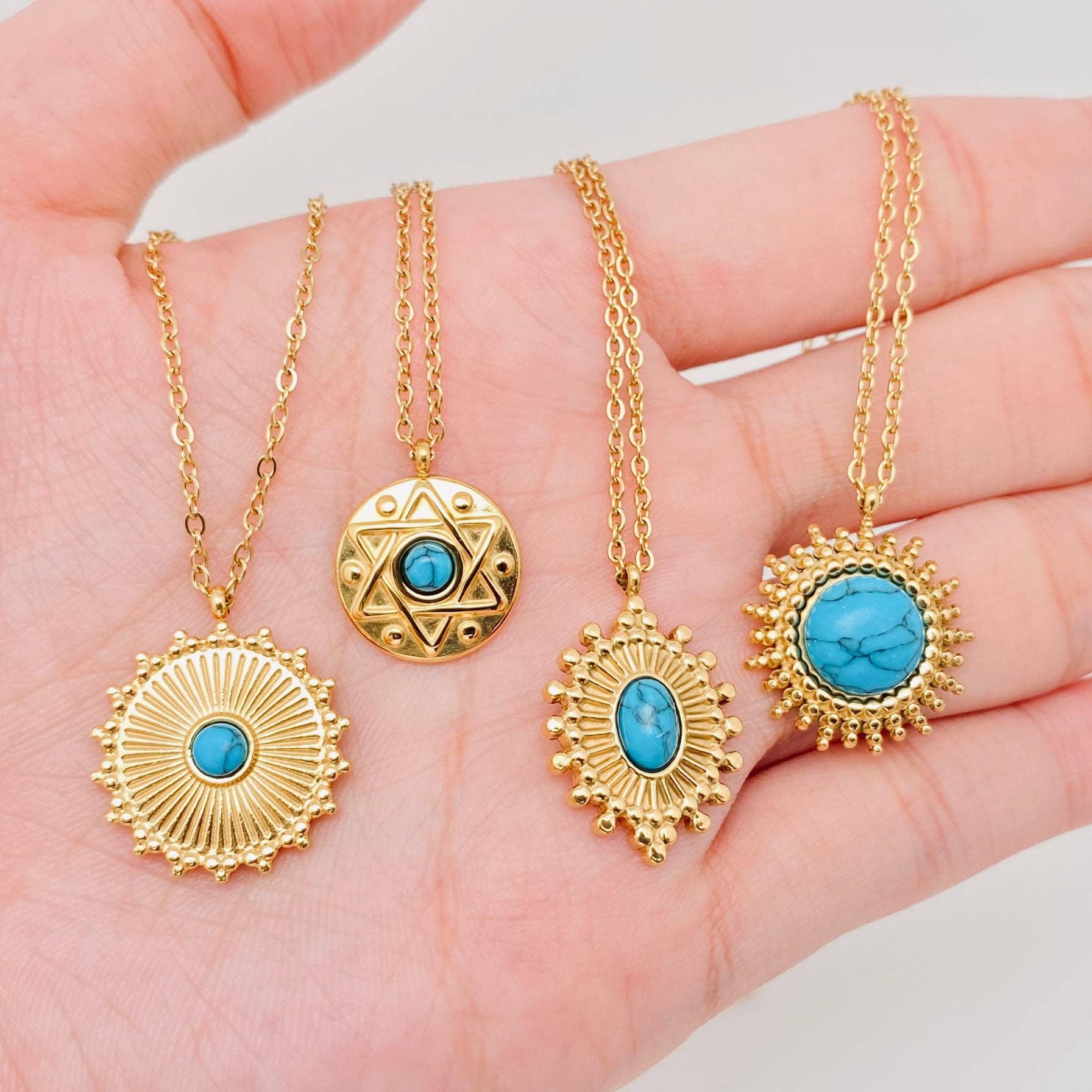 Gold necklaces with turquoise pendants held in a hand