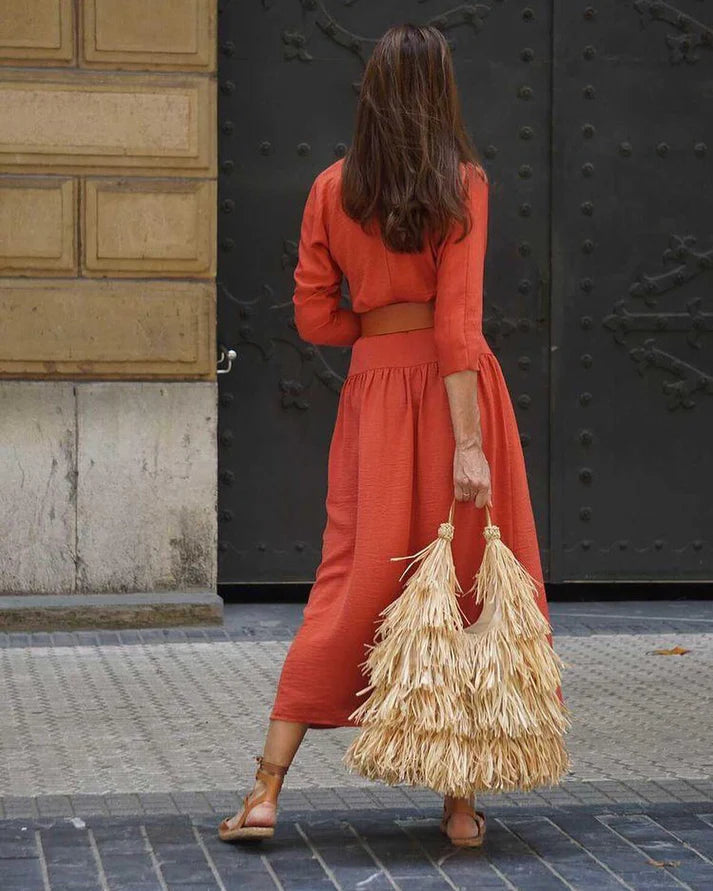 Woman carrying a natural raffia fringe shoulder bag.

