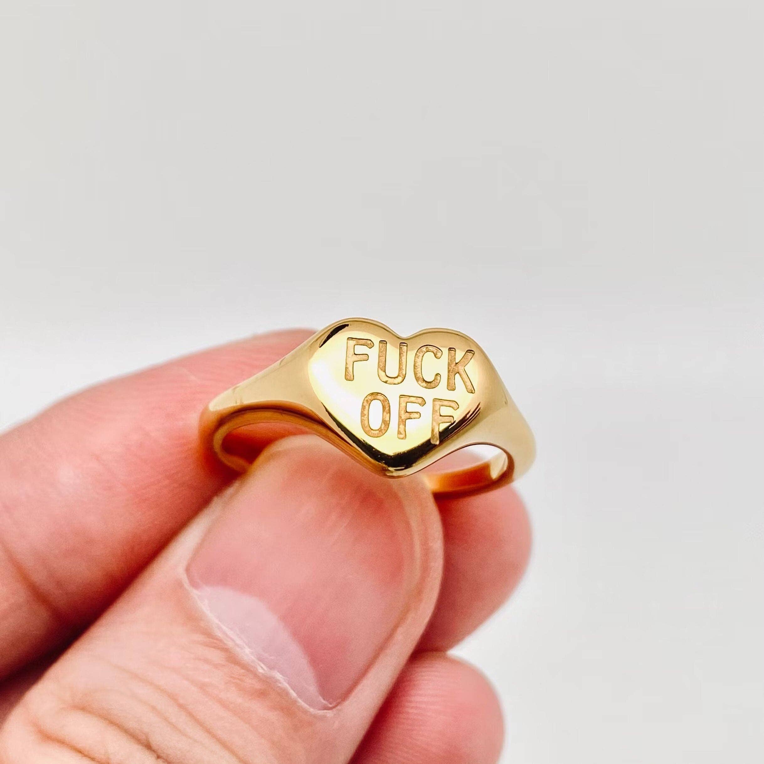 Gold sculptural heart ring with bold signet-inspired design held by hand