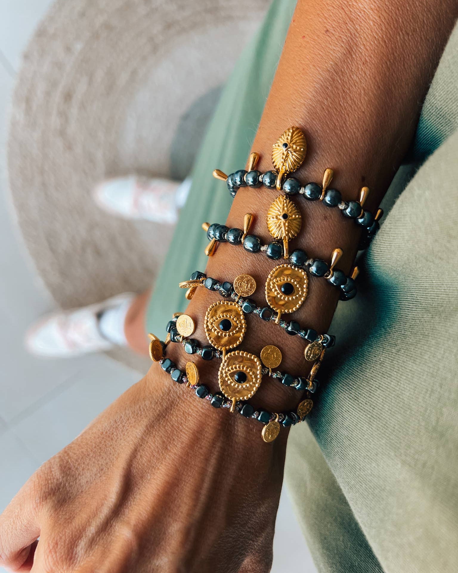 Close-up of a wrist wearing multiple gold and black beaded bracelets.