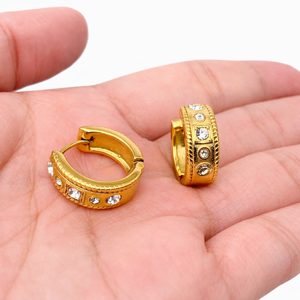 woman holding gold CZ huggie earrings