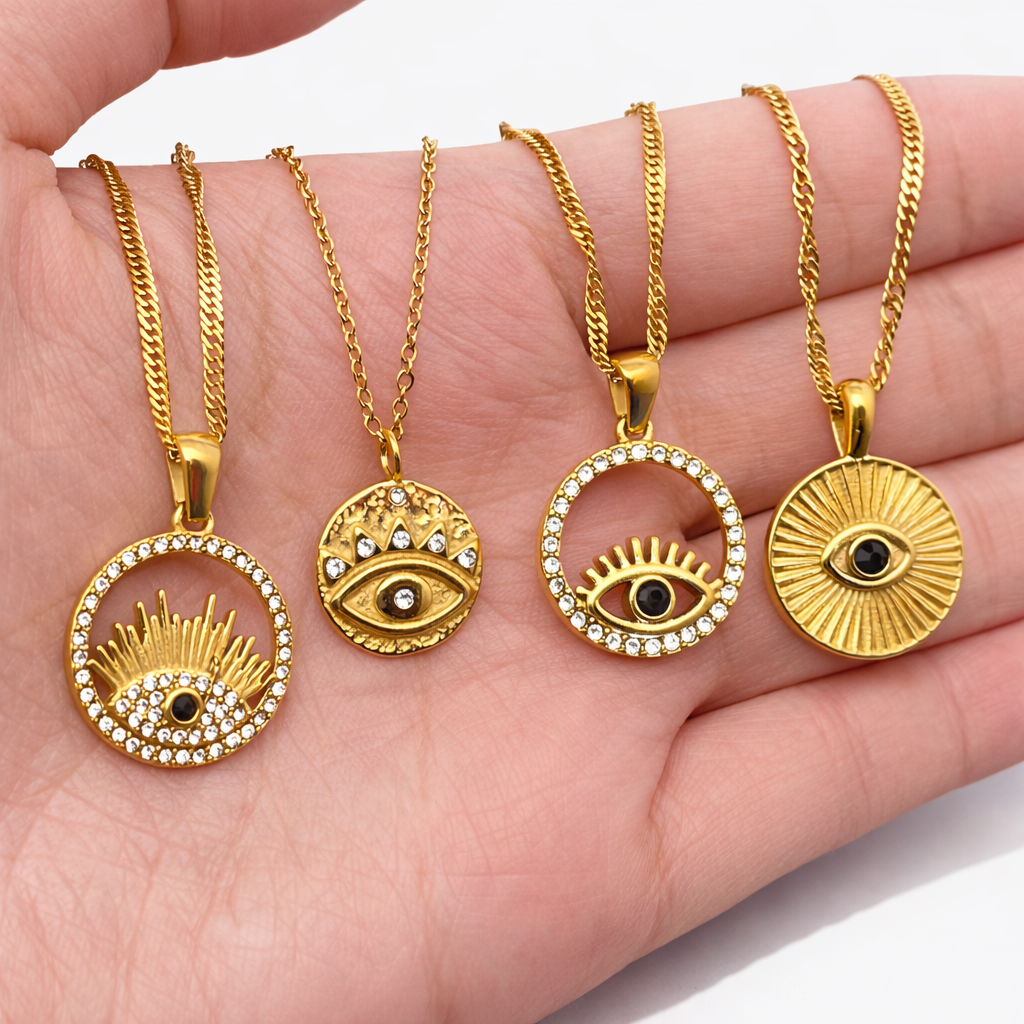 Hand holding layered gold evil eye necklaces with symbolic pendant detailing and polished finish.