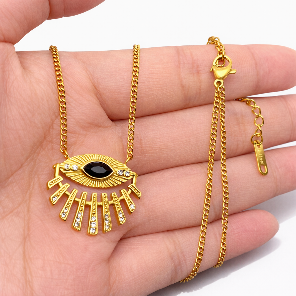 Gold necklace with an eye-shaped pendant held in a hand on a white background