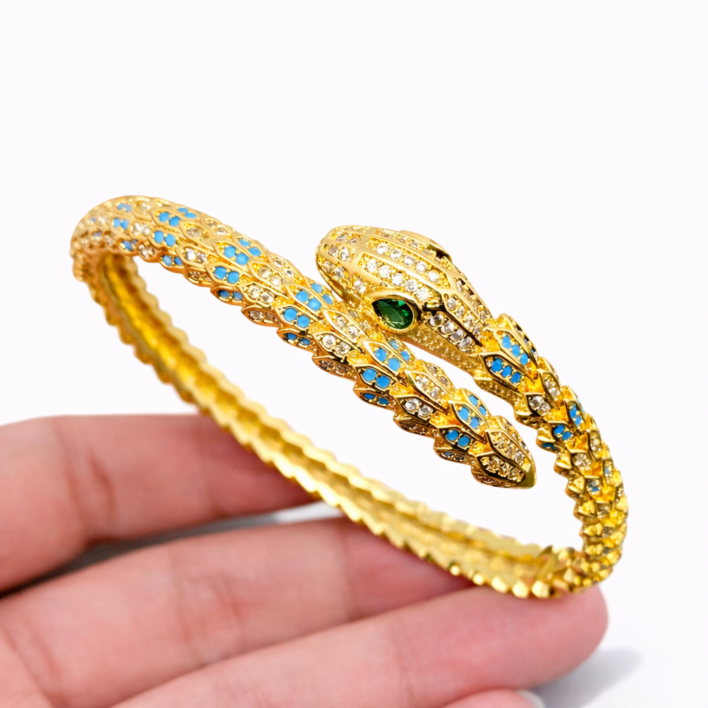 Gold-plated snake bangle with enamel detailing and shimmering rhinestone accents wrapped in a sculptural design.